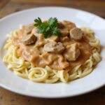 Servierfertiges Hähnchen Geschnetzeltes mit Nudeln und frischer Petersilie.
