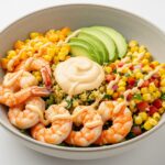 Fertige gegrillte Garnelen-Bowl mit Avocado, Maissalsa und cremiger Sauce, perfekt für gesunde Mahlzeiten.